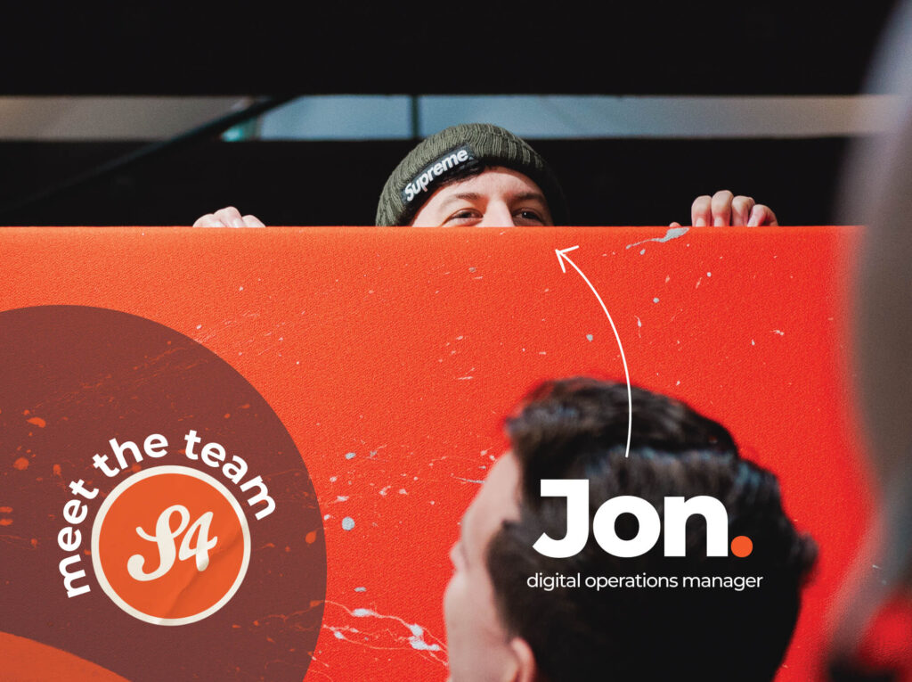 Meet the S4 Team - Sourcefour Digital Operations Manager Jon peeking over an orange room divider in the studio